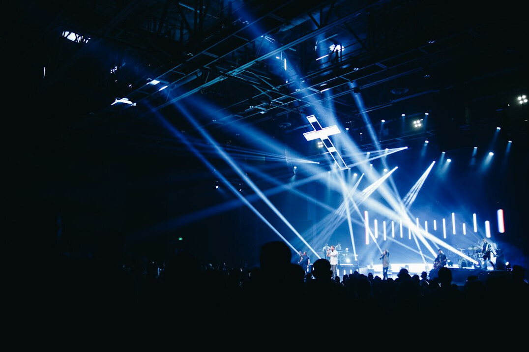 Concert stage with bright lights and silhouettes of a crowd